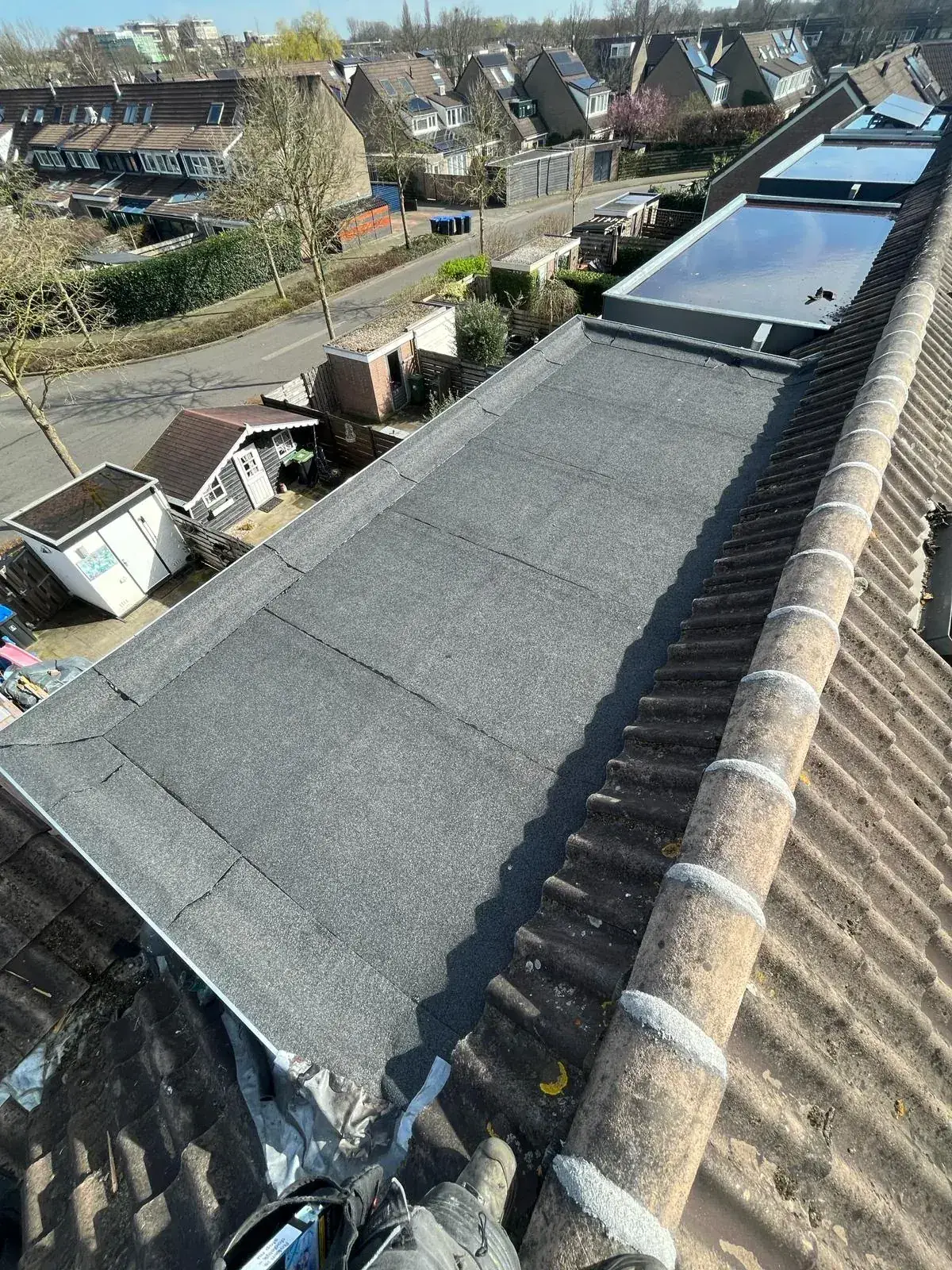 Nieuw plat bitumen dak tussen twee pannendaken, strak afgewerkt door Veilig Dak Nederland