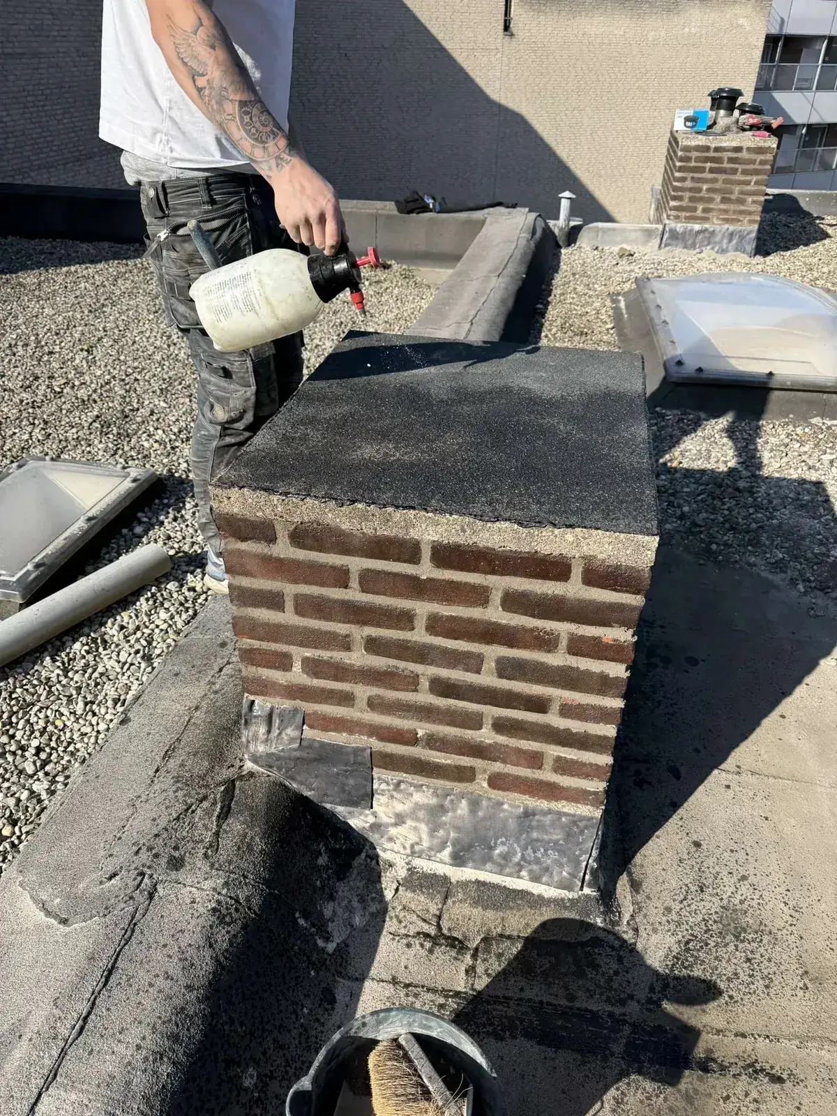 Dakdekker brandt bitumen rond schoorsteen met nieuw loodwerk op plat dak